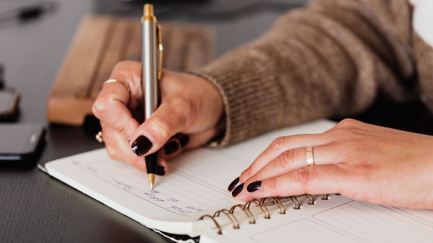 Closeup of person's hand writing on pad